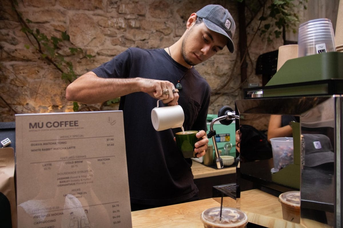Juan pouring a matcha latte behind the bar at Mù Coffee ATX